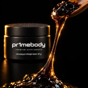 Extreme macro of dark glossy himalayan shilajit resin stretching in an amber-backlit strand from a wooden spoon, with the pr1mebody jar softly blurred behind