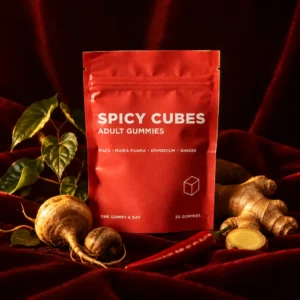 Spicy Cubes pouch beside maca root, ginger root, a red chili and epimedium leaves on red velvet